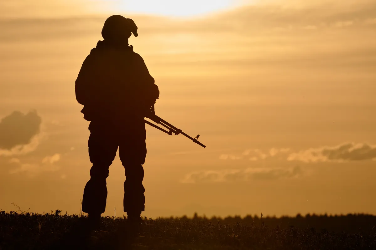 Military,Soldier,Silhouette,With,Machine,Gun,Over,Sunset